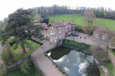 Salle de restaurant avec tables rondes dressées, nappes blanches, chaises en bois et éclairage tamisé.