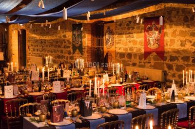 Salle de restaurant avec tables rondes dressées, nappes blanches, chaises en bois et éclairage tamisé.