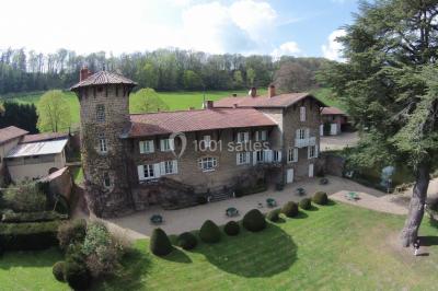 Salle de restaurant avec tables rondes dressées, nappes blanches, chaises en bois et éclairage tamisé.