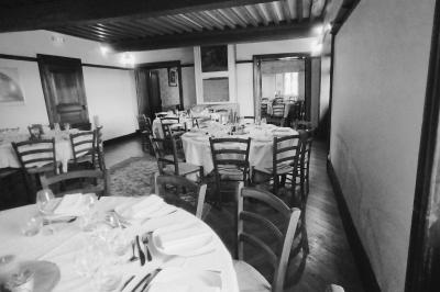 Salle de restaurant avec tables rondes dressées, nappes blanches, chaises en bois et éclairage tamisé.