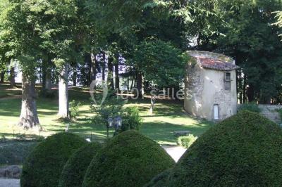 Salle de restaurant avec tables rondes dressées, nappes blanches, chaises en bois et éclairage tamisé.
