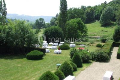 Salle de restaurant avec tables rondes dressées, nappes blanches, chaises en bois et éclairage tamisé.