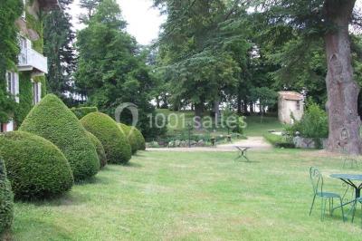 Salle de restaurant avec tables rondes dressées, nappes blanches, chaises en bois et éclairage tamisé.