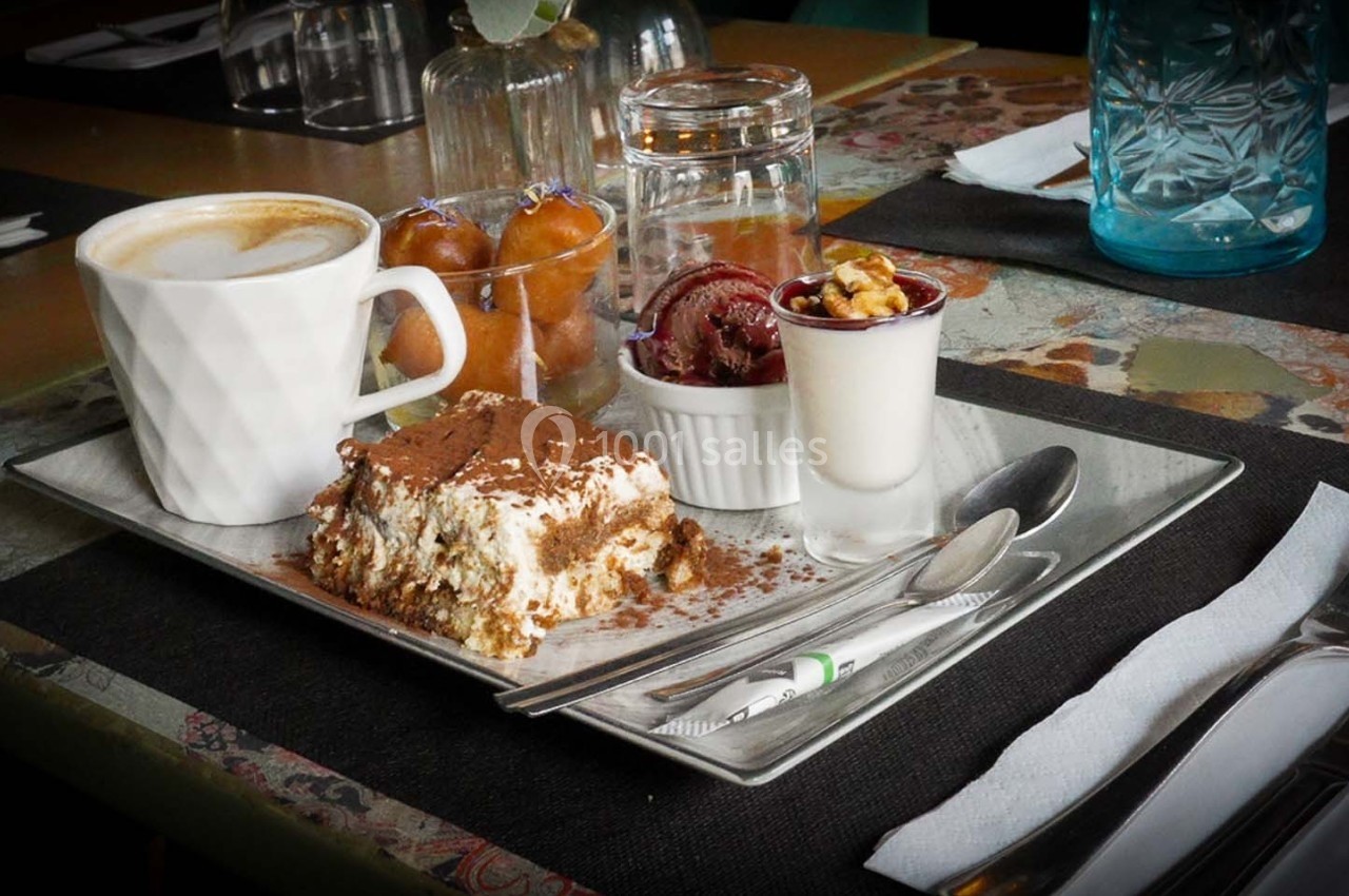 Plateau de desserts avec tiramisu, panna cotta, fruits secs, café et douceurs sur une table dressée.