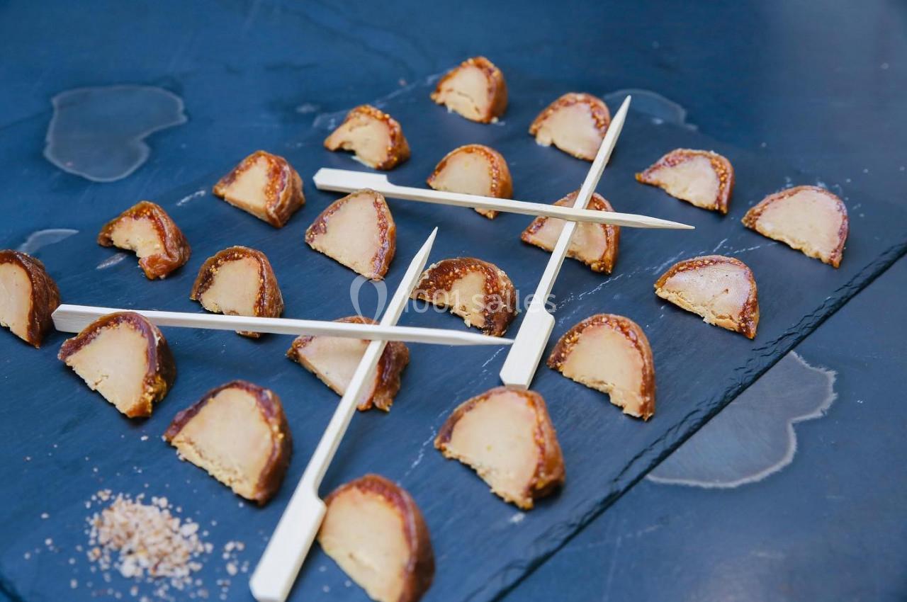 Morceaux de foie gras en croûte disposés sur une ardoise avec des piques en bois pour le service.