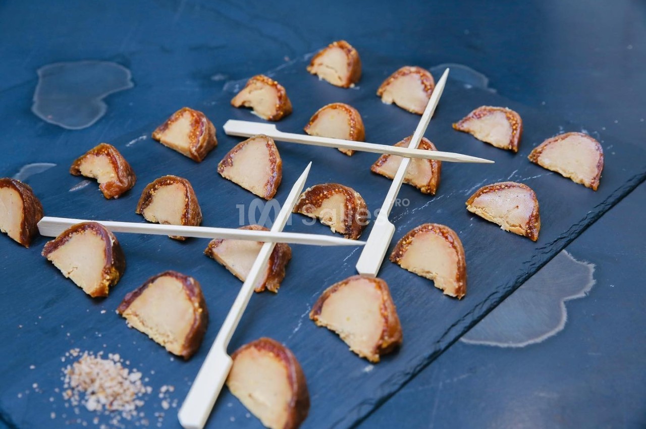 Morceaux de foie gras en croûte disposés sur une ardoise avec des piques en bois pour le service.