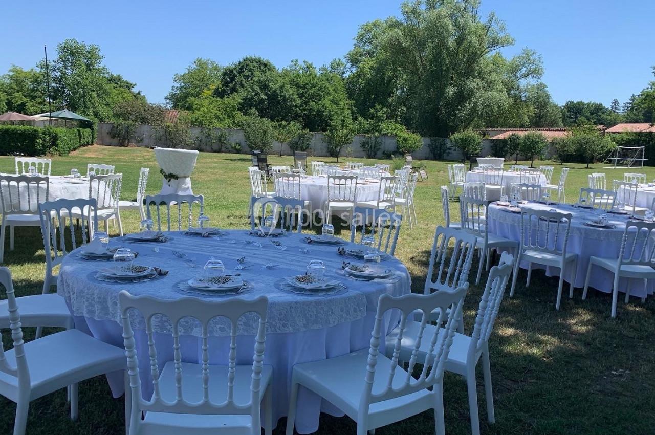 Location salle Cleppé (Loire) - L'Orangerie de Châtel #7 Tables rondes dressées avec nappes blanches et chaises disposées en extérieur sur une pelouse, par une journée ensoleillée.