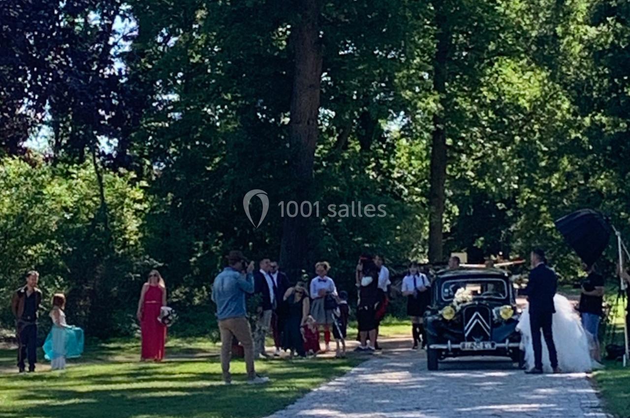 Location salle Cleppé (Loire) - L'Orangerie de Châtel #31 Un groupe de personnes rassemblé près d'une voiture ancienne décorée, dans un parc verdoyant.