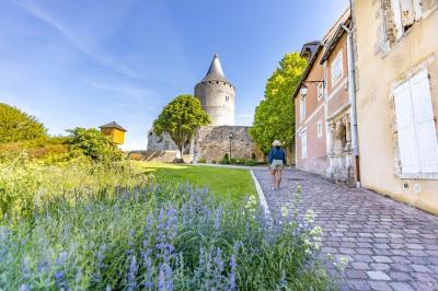 Salle de conférence vide avec des rangées de chaises noires, un écran de projection et des tables à l'avant.