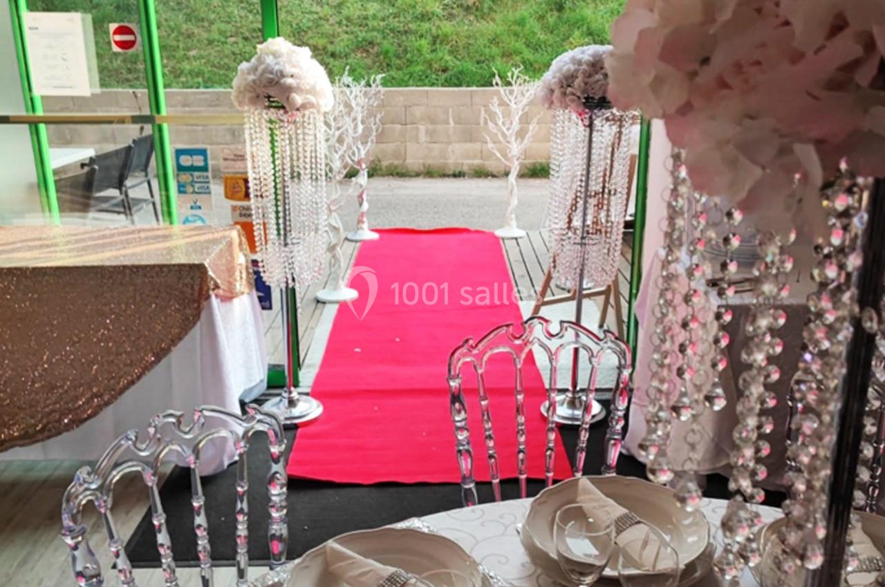Chemin rouge bordé de décorations élégantes avec cristaux et fleurs, menant à une entrée vitrée.