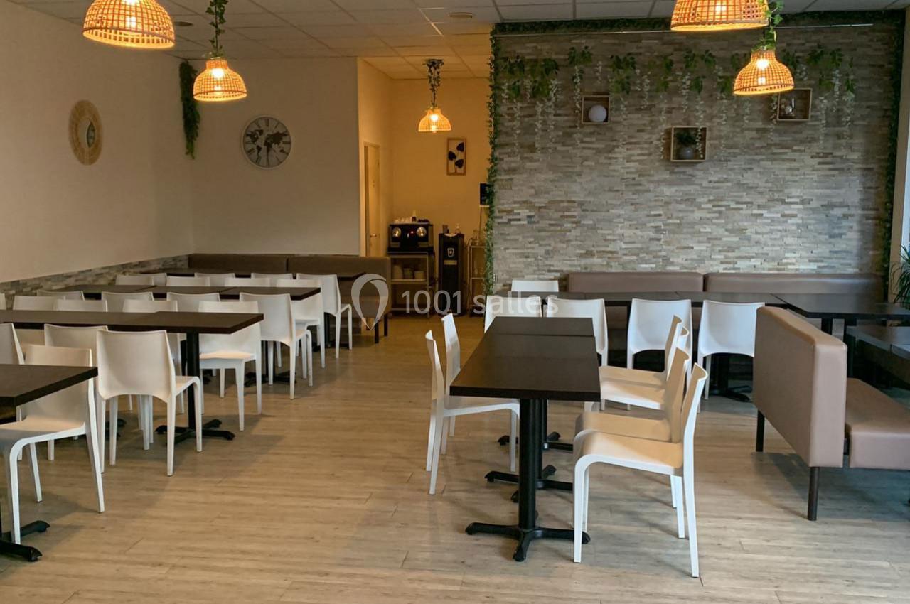 Salle de restaurant moderne avec tables en bois, chaises blanches, banquettes marron et décoration murale végétale.