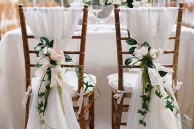 Table élégamment dressée avec nappes blanches, chemins de table verts, serviettes pliées et décorations florales.