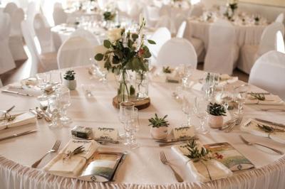 Table élégamment dressée avec nappes blanches, chemins de table verts, serviettes pliées et décorations florales.