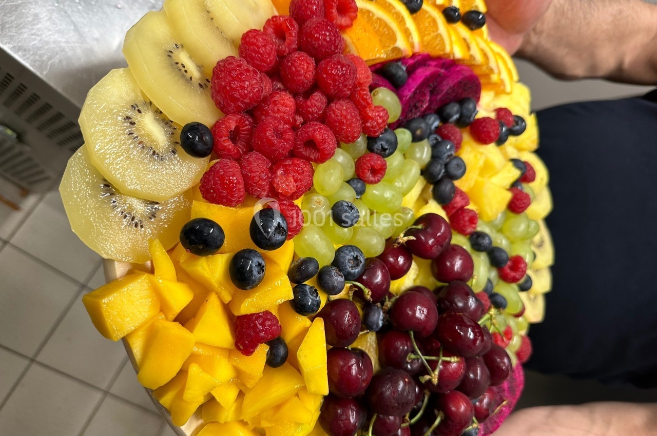 Plateau coloré de fruits variés comprenant kiwis, oranges, framboises, myrtilles, raisins, cerises, mangues et pitayas.