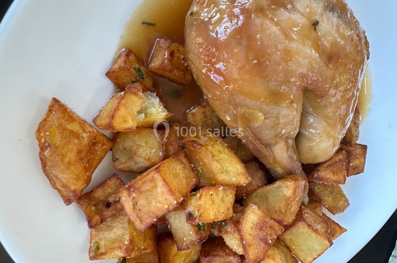 Poulet rôti nappé de sauce servi avec des pommes de terre dorées sur une assiette blanche.