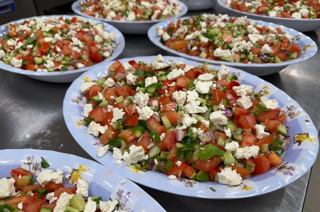 Assiettes de salade composée de tomates, concombres, poivrons, oignons rouges et fromage émietté.