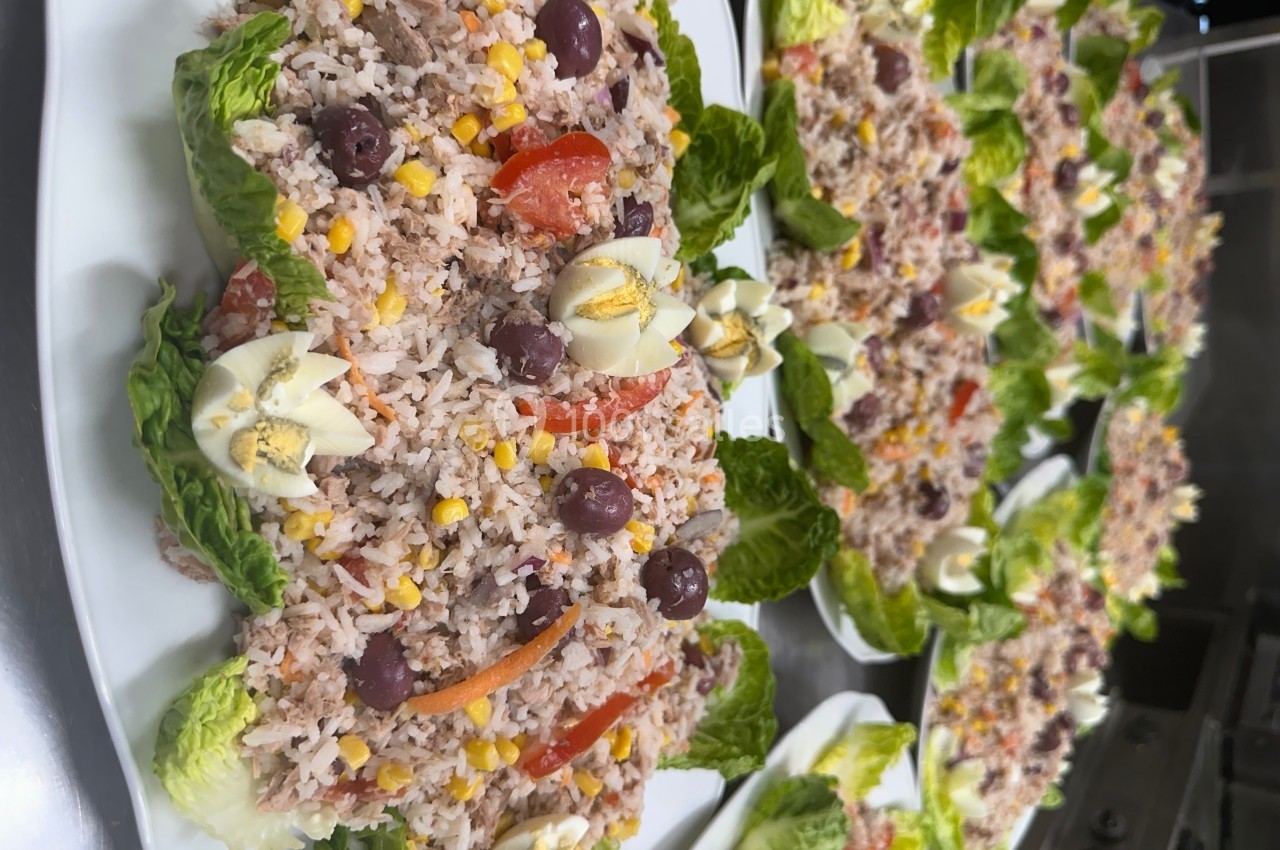 Assiettes de salade composée avec riz, thon, maïs, olives, tomates, œufs décorés et feuilles de laitue.