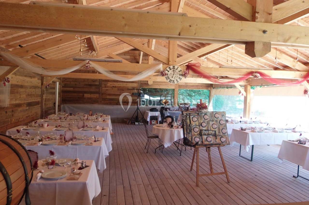 Location salle Ornacieux (Isère) - Domaine du Moulin Piongo #13 Salle en bois décorée pour un événement, avec des tables dressées et un chevalet exposant une toile.