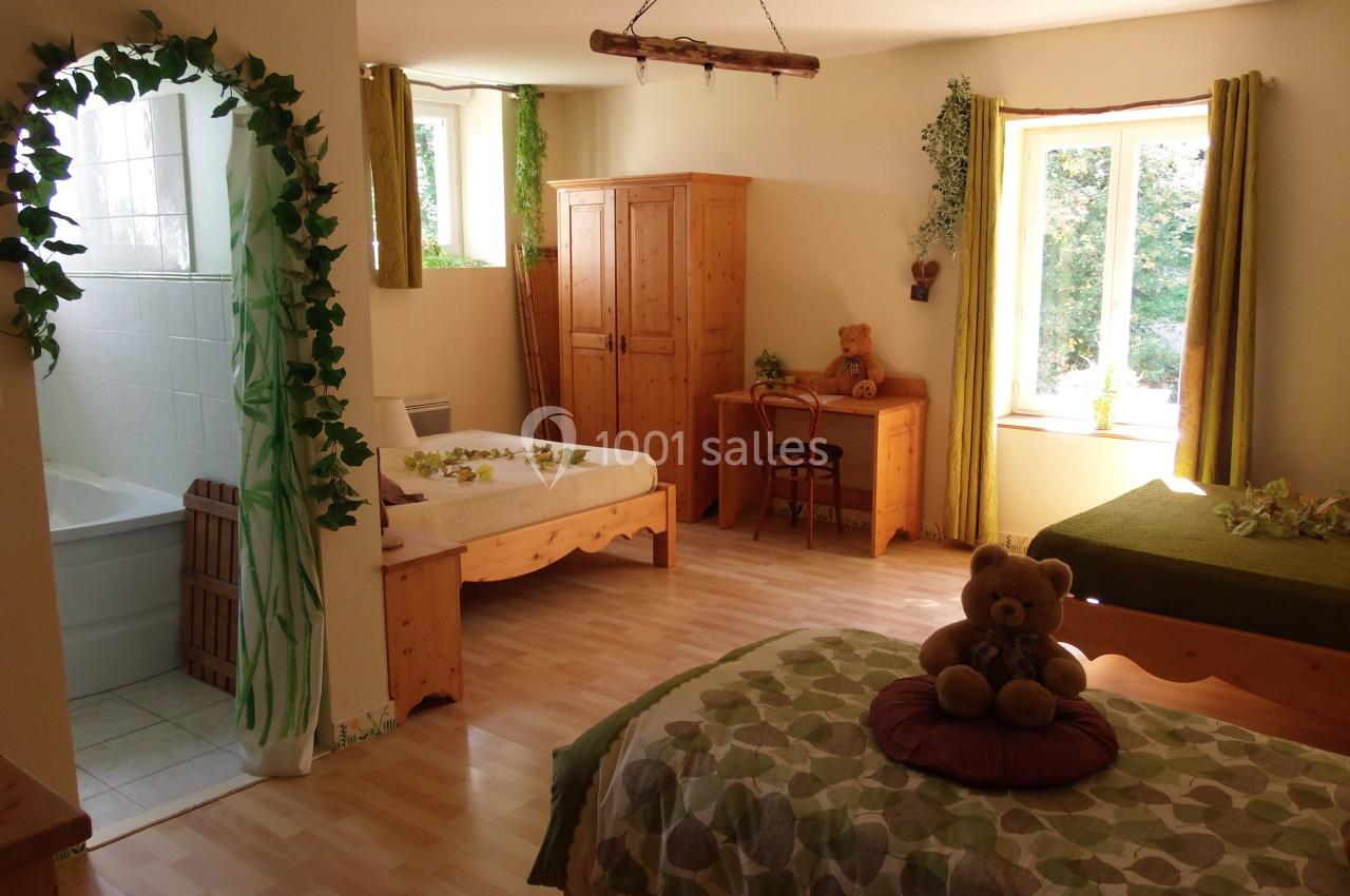 Location salle Ornacieux (Isère) - Domaine du Moulin Piongo #29 Chambre lumineuse avec lits en bois, bureau, armoire, décorations végétales et vue sur un jardin par la fenêtre.