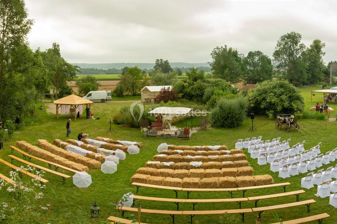 Location salle Ornacieux (Isère) - Domaine du Moulin Piongo #3 Disposition d'une cérémonie en plein air avec bottes de paille en guise de sièges et allée centrale, entourée de verdure.
