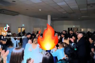Salle de réception décorée pour un mariage, avec tables dressées, fleurs blanches et rouges, et arche florale en arrière…
