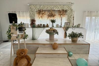 Salle de réception décorée pour un mariage, avec tables dressées, fleurs blanches et rouges, et arche florale en arrière…