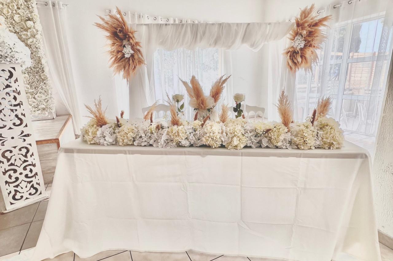 Table décorée avec des fleurs blanches et des ornements de pampas dans une salle lumineuse aux tons neutres.