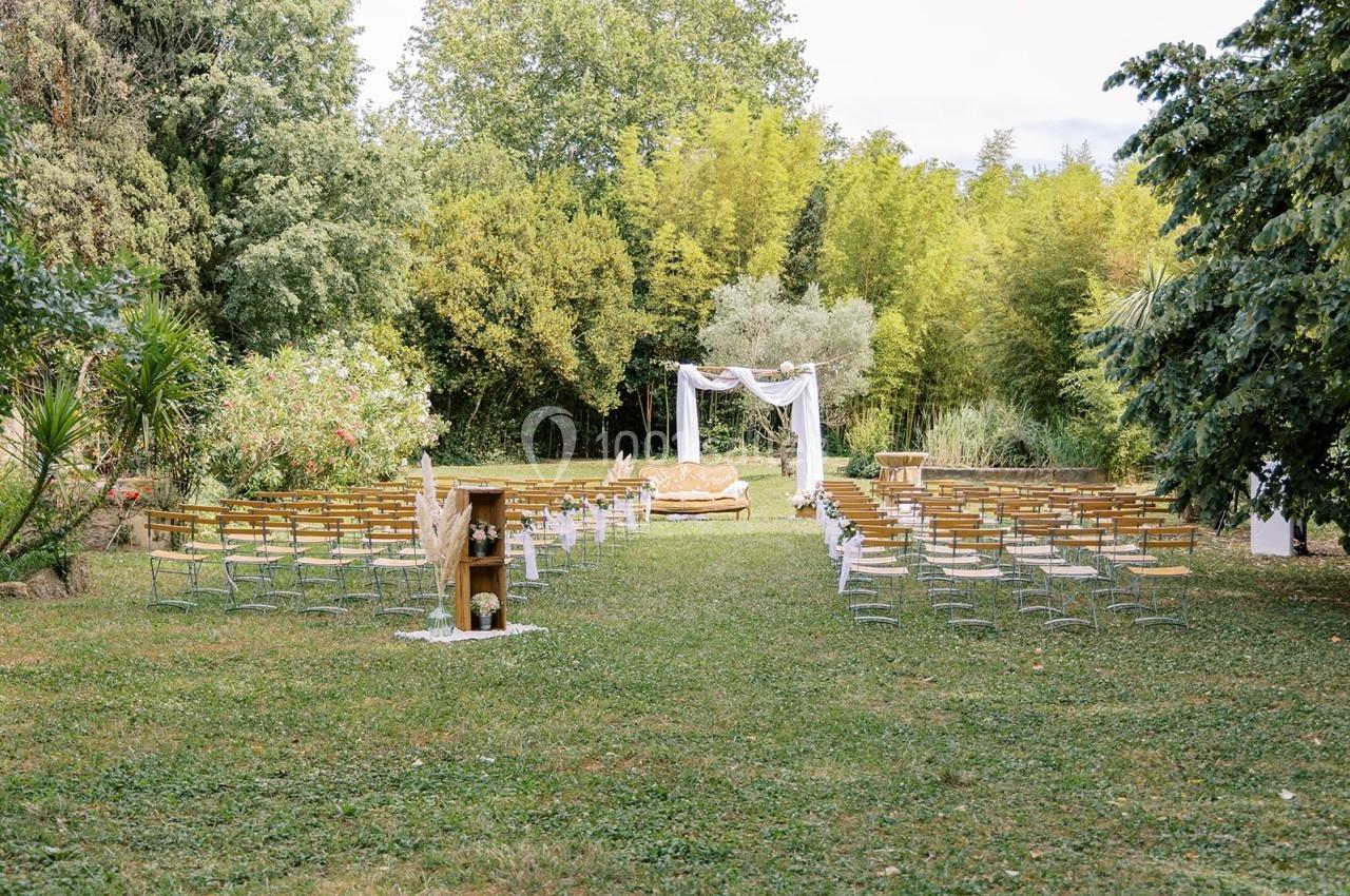 Chaises disposées en rangées sur une pelouse, face à une arche décorée pour une cérémonie en plein air.
