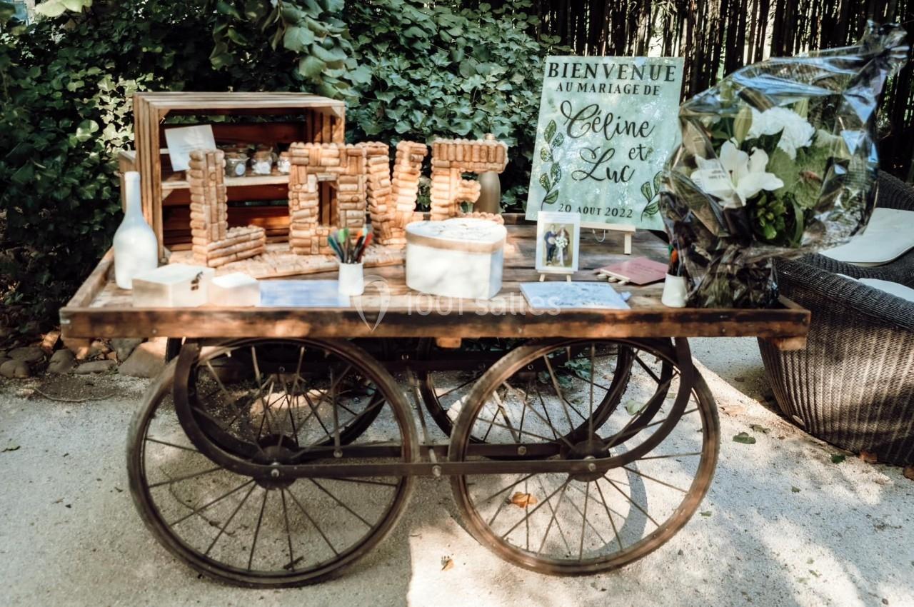 Table décorative en bois avec des bouchons formant le mot ’LOVE’, des fleurs et une pancarte de mariage.