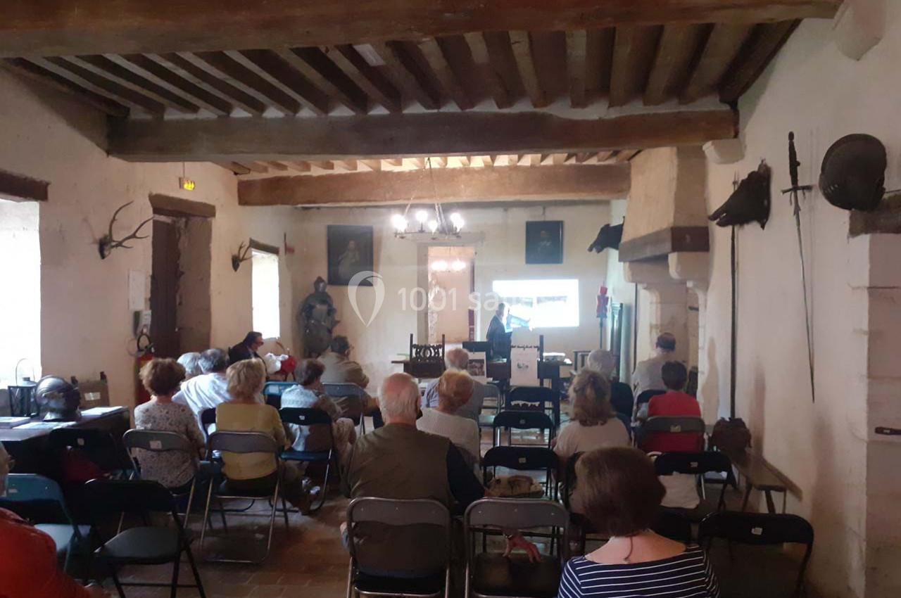 Personnes assises dans une salle ancienne, écoutant une présentation projetée sur un écran.