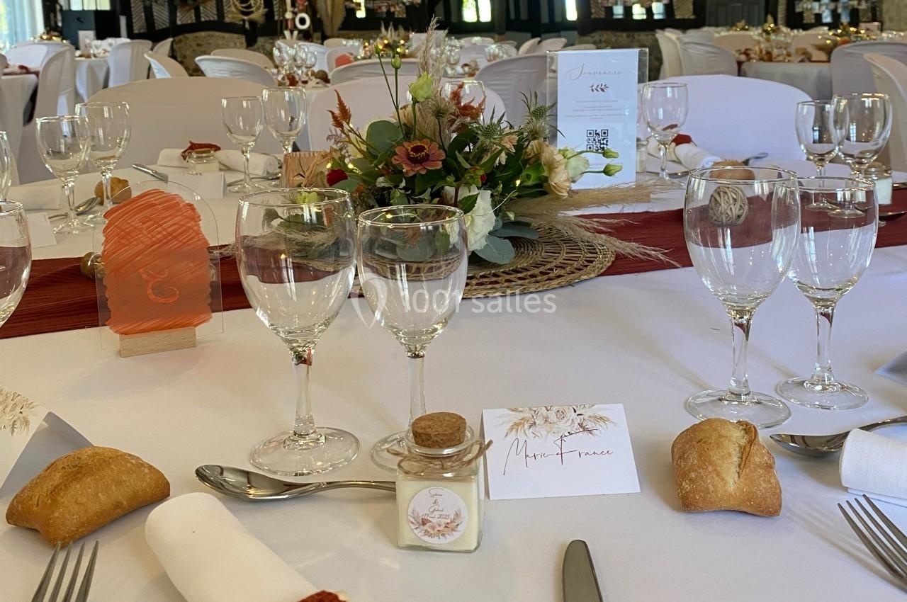 Location salle Beaubray (Eure) - Auberge de la Comtesse #11 Table de réception décorée avec des fleurs, menus, verres, couverts et petits pains disposés sur une nappe blanche.