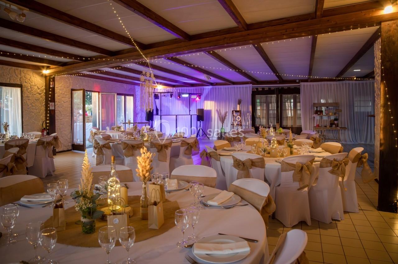 Location salle Beaubray (Eure) - Auberge de la Comtesse #3 Salle de réception décorée avec des tables rondes, nappes blanches, chaises ornées de nœuds beige et éclairage chaleureux.