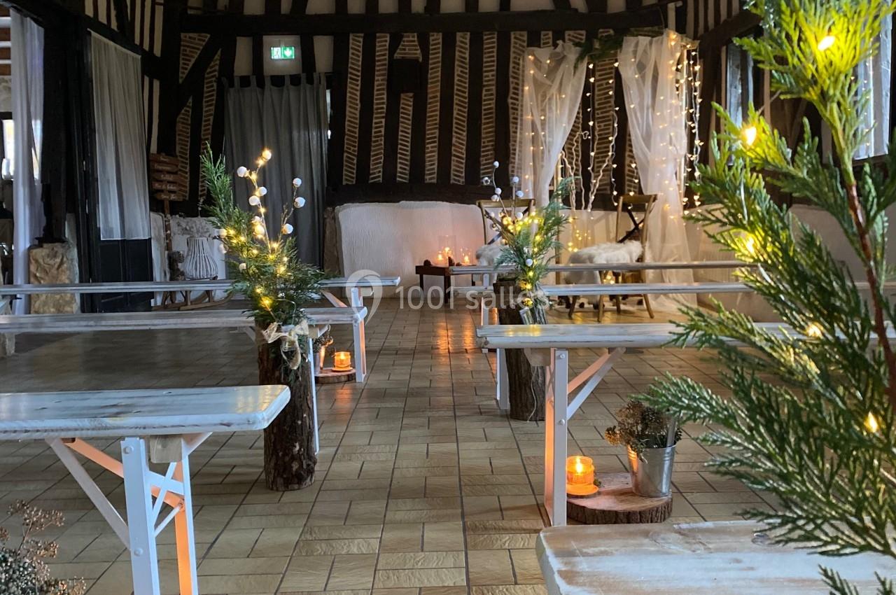 Mariage d'hiver - cérémonie laïque - Auberge de la comtesse Salle décorée pour un événement, avec bancs en bois, bougies, guirlandes lumineuses et plantes sur un sol carrelé.