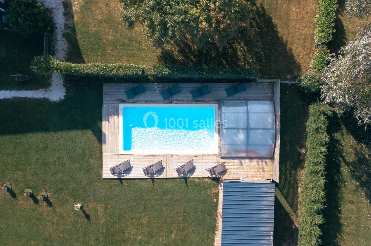 Piscine - Jardin de reception - Auberge de la comtesse Vue aérienne d'une piscine rectangulaire entourée de transats sur une terrasse en bois, dans un jardin verdoyant.