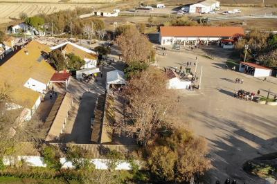 Grande salle vide avec un sol en pierre, plafond en bois avec poutres apparentes et lustres suspendus, décorée de plantes.