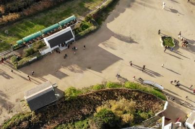 Grande salle vide avec un sol en pierre, plafond en bois avec poutres apparentes et lustres suspendus, décorée de plantes.