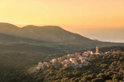 Miniature Corsica Convention Bureau #7 Paysage montagneux au coucher du soleil avec une personne debout sur un promontoire rocheux, entourée de végétation.