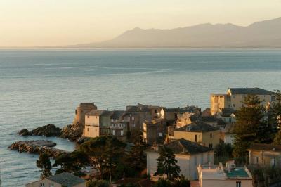 Miniature Corsica Convention Bureau #5 Paysage montagneux au coucher du soleil avec une personne debout sur un promontoire rocheux, entourée de végétation.