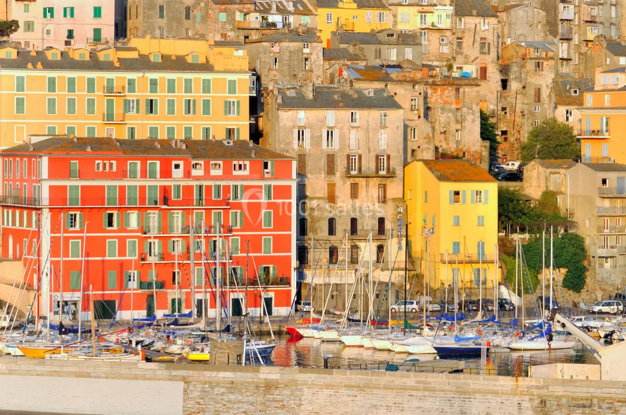 Façades colorées et bateaux amarrés dans un port méditerranéen baigné par la lumière du soleil.