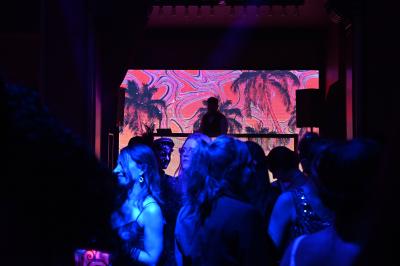 Miniature DJ Vincennes (Val-de-Marne) - Frank Merry #4 Personnes dansant et discutant dans une ambiance tamisée de boîte de nuit avec un écran lumineux en arrière-plan.