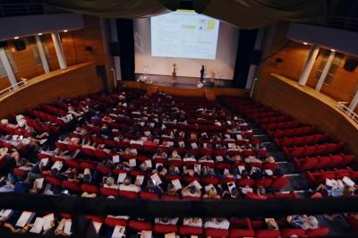 Tables de banquet en plein air avec nappes à carreaux rouges et blanches, disposées sous un arbre dans un cadre champêtre.