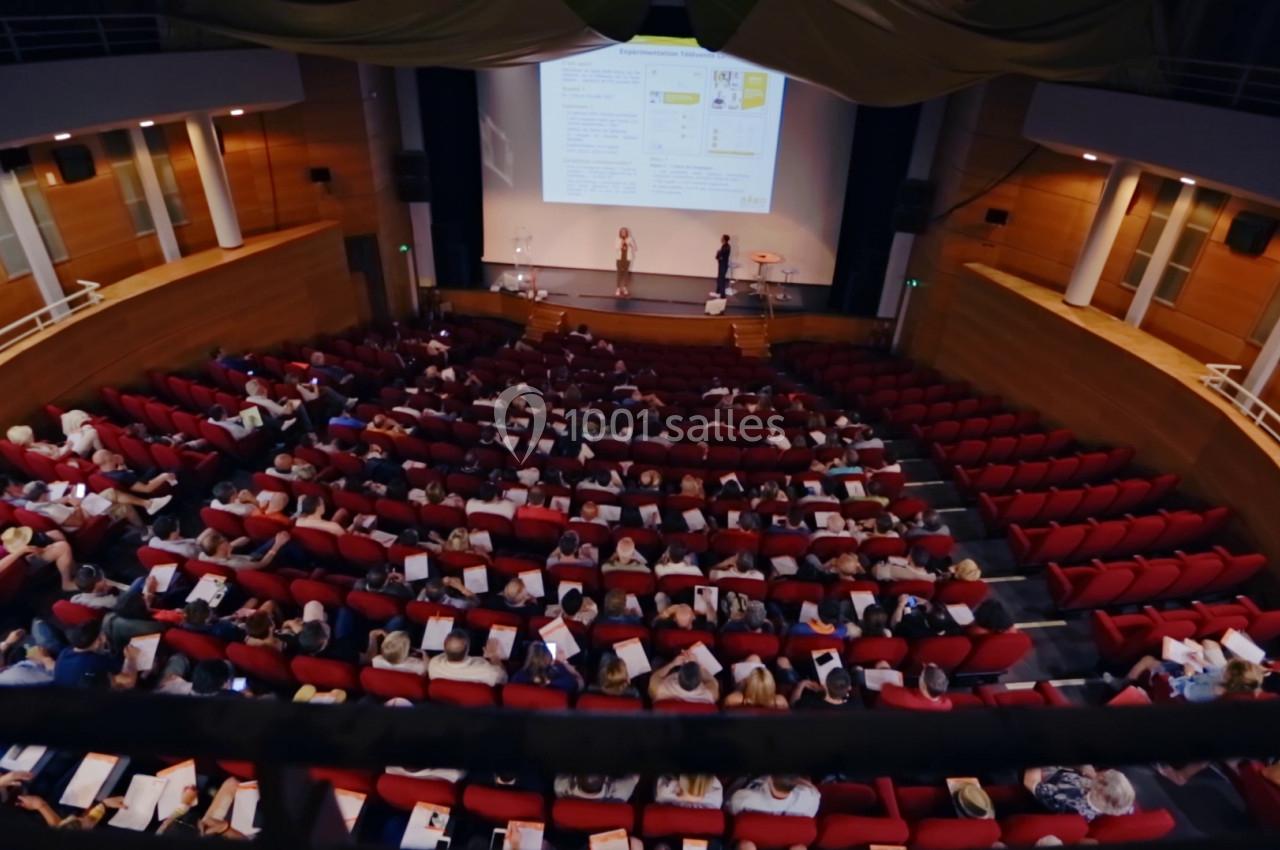 Vue d'une salle de conférence avec des participants assis et un écran projetant une présentation.
