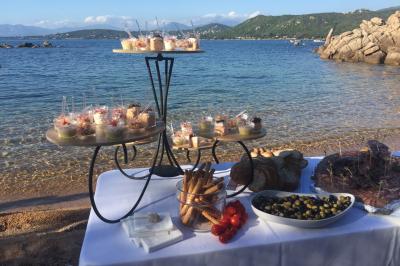 Tente transparente installée sur une plage, aménagée avec des chaises blanches et des plantes décoratives.