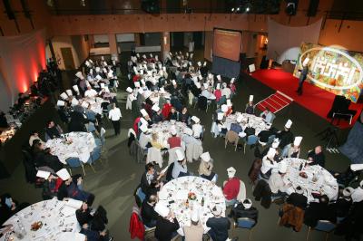 Tente transparente installée sur une plage, aménagée avec des chaises blanches et des plantes décoratives.