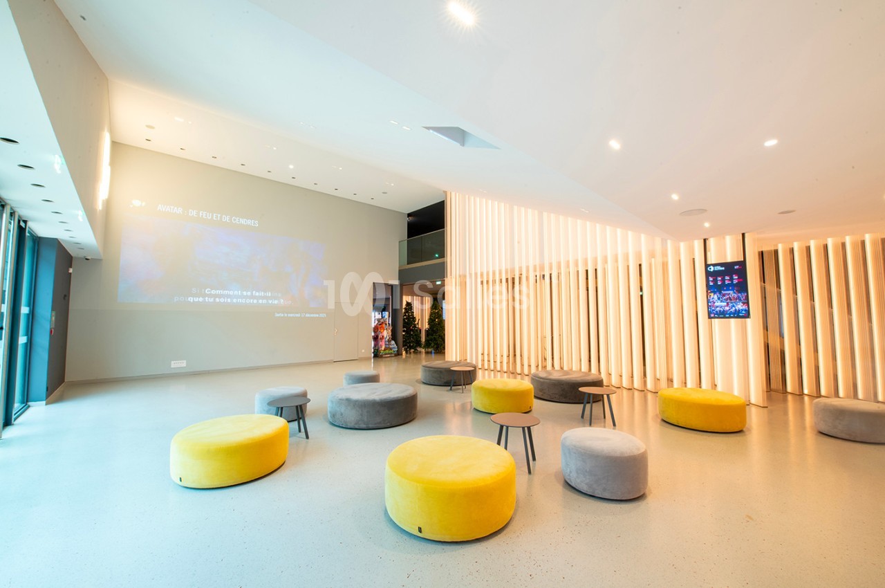 Espace intérieur moderne avec des poufs colorés, un sol clair et des panneaux lumineux en bois.