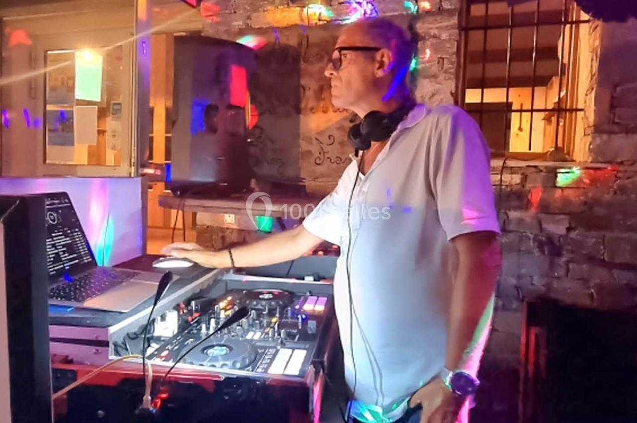 Un DJ mixe de la musique sur une console dans un espace éclairé par des lumières colorées.