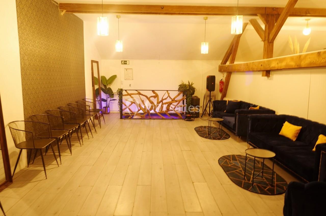 Salle lumineuse avec parquet clair, canapés bleus, chaises métalliques, plantes et décoration moderne en bois.