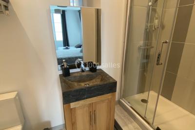 Chambre avec lit double, douche accessible, sol en parquet clair et éclairage moderne.