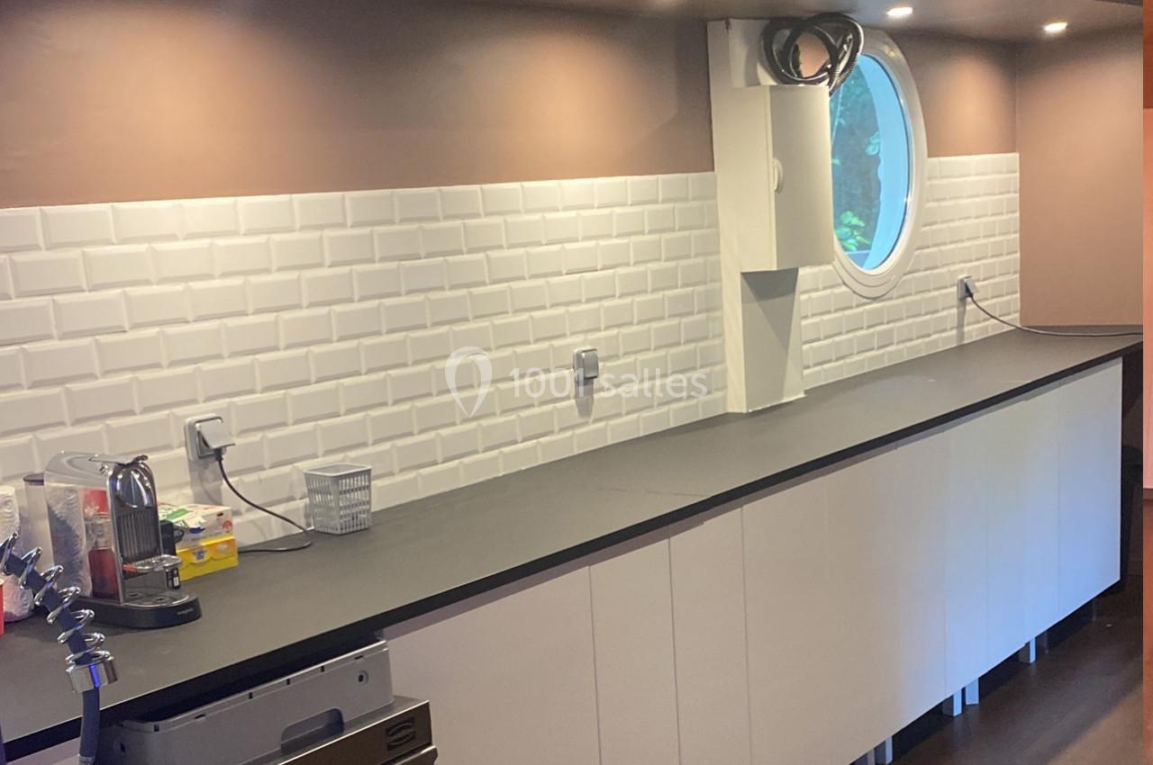 Plan de travail de cuisine moderne avec crédence en carrelage blanc, éclairage intégré et fenêtre ronde.