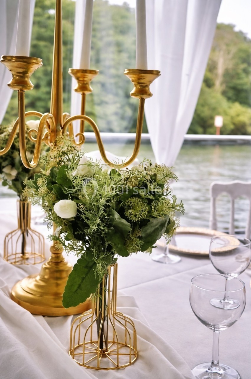 Bouquet de fleurs vertes et blanches sur une table décorée avec un chandelier doré, près d'une fenêtre donnant sur un…